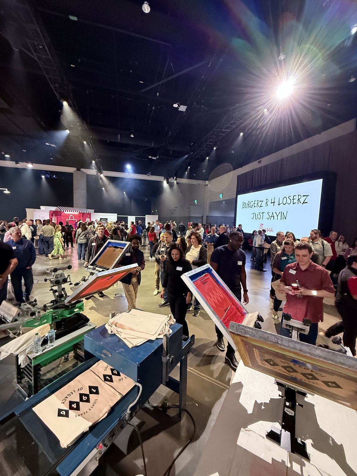 Wide ballroom floor with guests circulating between live pressing stations